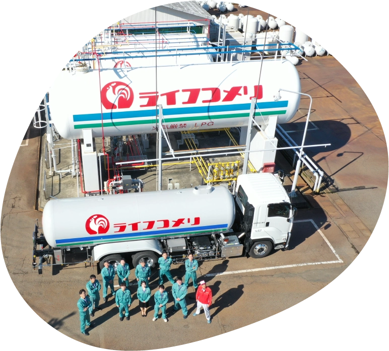 ライフコメリのタンクをバックに社員が並んでいる写真